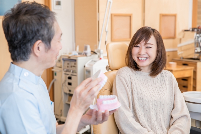 歯科医師から歯の模型を用いて説明を受けて安心している患者の様子。